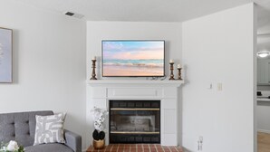 Un salon avec une cheminée, un canapé gris et un tableau encadré accroché au mur.