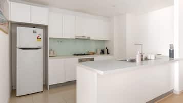 Una cocina moderna con armarios blancos, una isla integrada y un refrigerador de acero inoxidable.