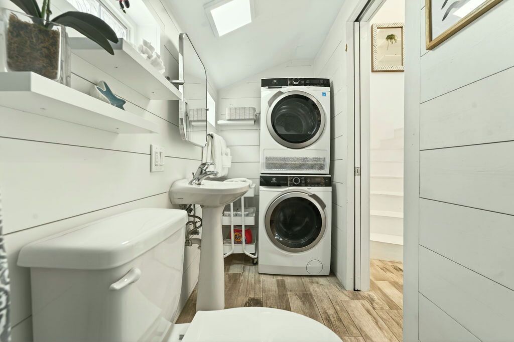 A compact laundry room with a washing machine, a sink, and a toilet.