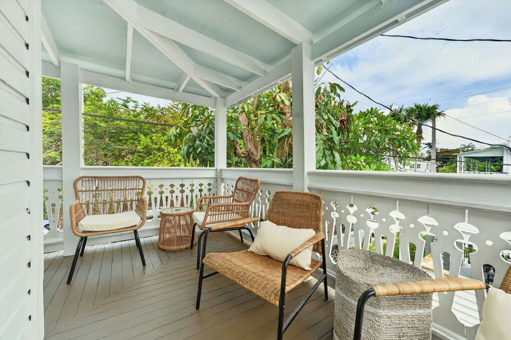 A covered porch with wicker furniture and a white picket fence.