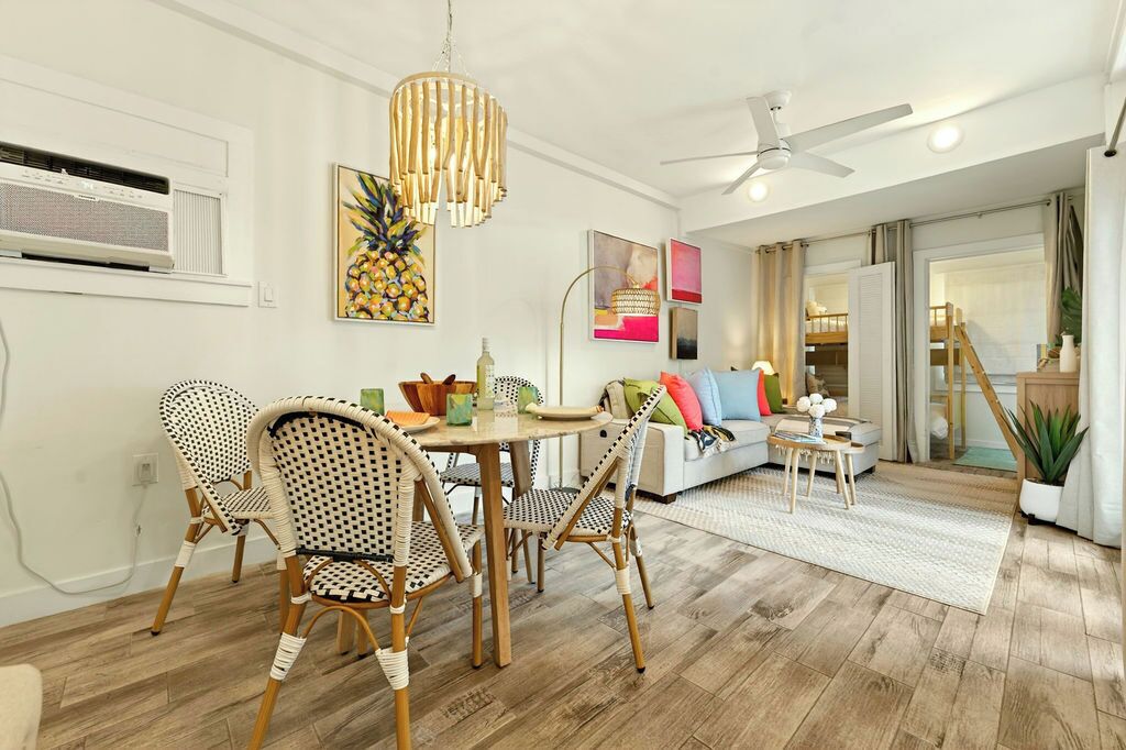 A dining area with wicker chairs, a round table, and a pendant light.