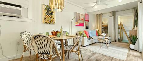 A dining area with wicker chairs, a round table, and a pendant light.