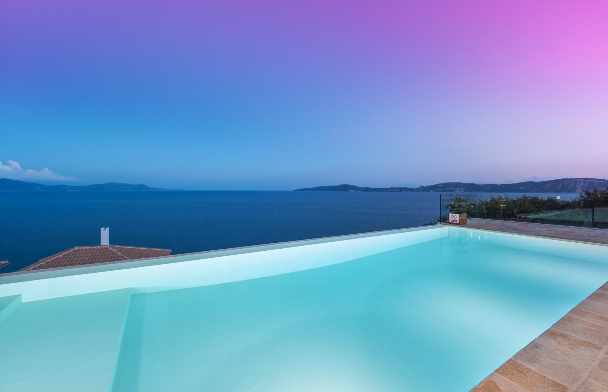 Une piscine avec vue sur la mer et les montagnes lointaines.