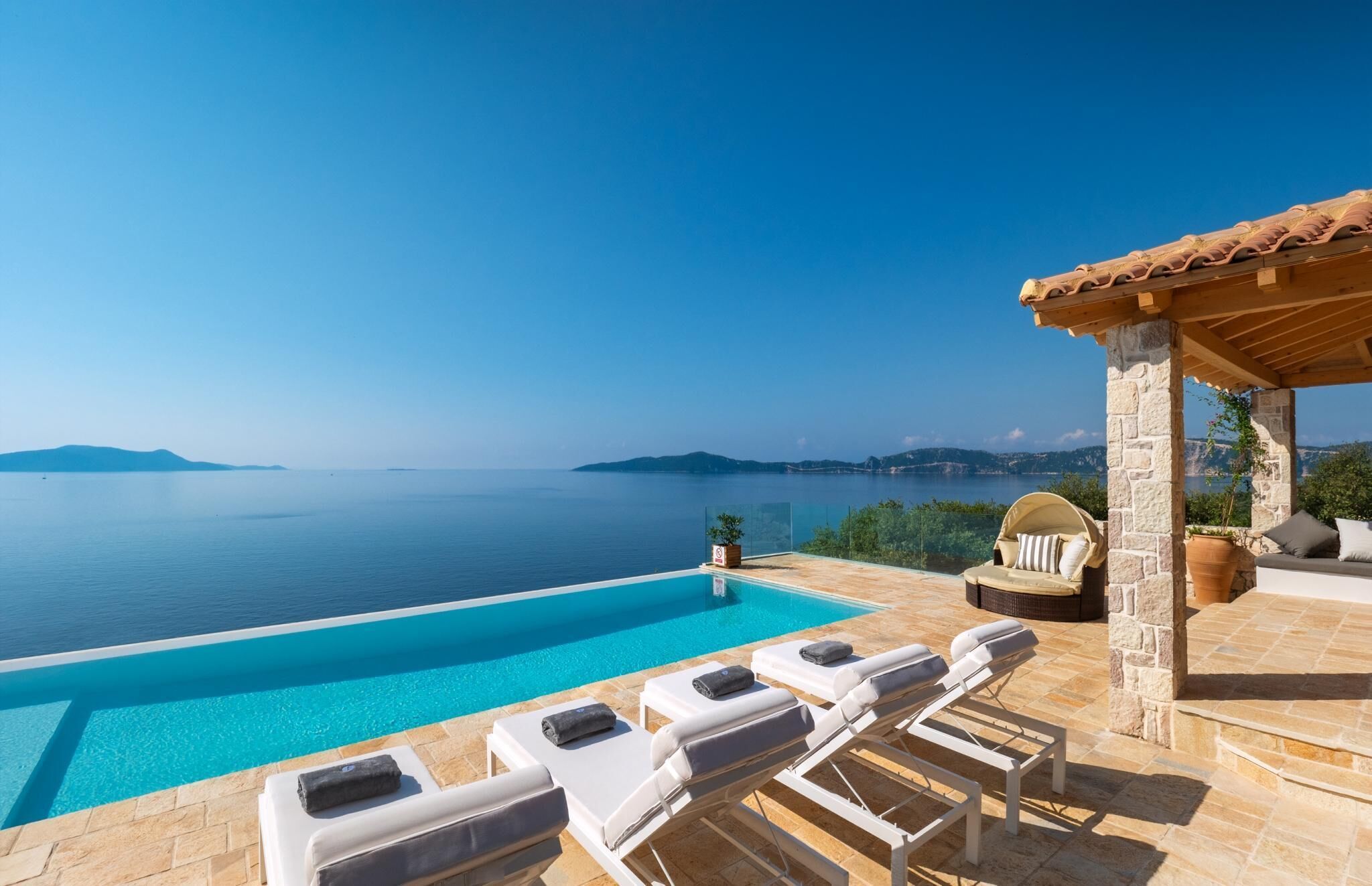 A pool with lounge chairs, a stone structure, and a view of the sea.