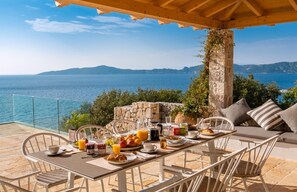 Ein Tisch ist für das Frühstück gedeckt, mit Blick auf das Meer und die Berge.