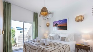 A bedroom with a bed, bedside tables, a lamp, a picture on the wall, and a view through a window. - Casa Alvor - Rooftop Jacuzzi with Sea Views (Alvor)