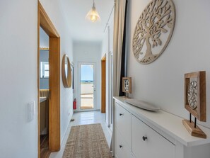 A hallway with a wooden door leading to a balcony, a white dresser with a mirror, and a wall-mounted tree decoration. - Apartment Alvor - Rooftop Jacuzzi with Sea Views (Alvor)