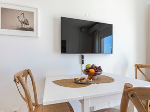 A dining area with a white table, chairs, a bowl of fruit, and a framed picture on the wall. - Apartment Alvor - Rooftop Jacuzzi with Sea Views (Alvor)
