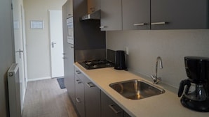 A modern kitchen with grey cabinets, a stainless steel sink, and a coffee maker. - Duinlodge 4 + 2 (Noordwijk)
