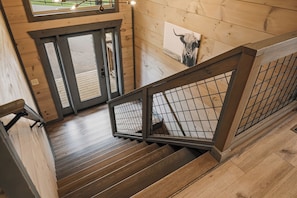 Eine Holztreppe mit Metallgeländer, die zu einer Tür mit Glasscheiben führt.