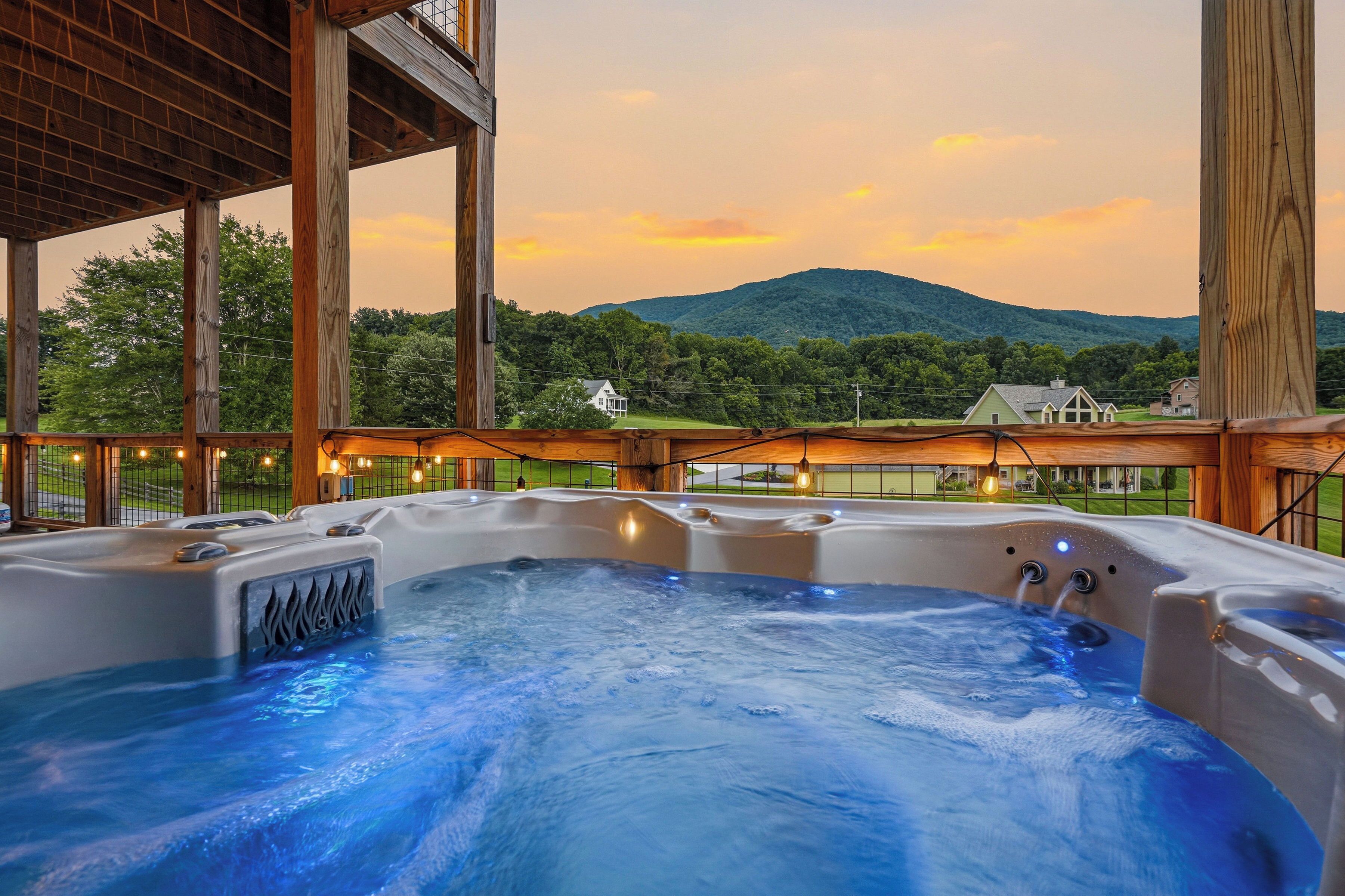 A hot tub with a view of a mountain and houses in the background.