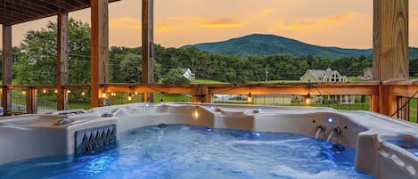 A hot tub with a view of a mountain and houses in the background.