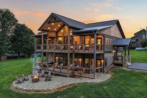 Ein mehrstöckiges Holzhaus mit Feuerstelle, Sitzgelegenheiten und einer großen Terrasse.