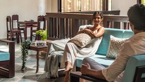 A room with a high ceiling, wooden beams, a sofa, a table with chairs, and hanging lamps. - Kumberi Manor by Raho Heritage Retreat in Coorg (Ammathi)