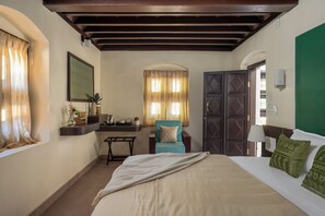 Camera d'albergo con un letto, una sedia, una scrivania e una parete verde.