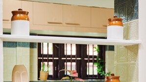 A kitchen shelf with decorative items, a microwave, and a window with a view. - Kumberi Manor by Raho Heritage Retreat in Coorg (Ammathi)