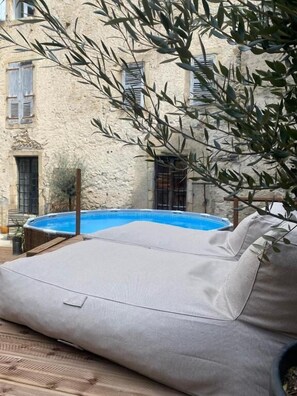 A poolside area with a beige lounge chair, a swimming pool, and a building with stone walls and windows. - Dreamhome B&B Limoux (Limoux)