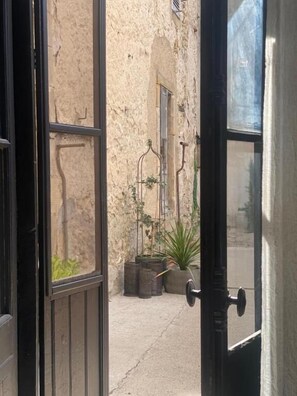 Une porte ouverte donnant sur une ruelle Ă©troite, avec un pot de fleurs et une fenĂȘtre.
