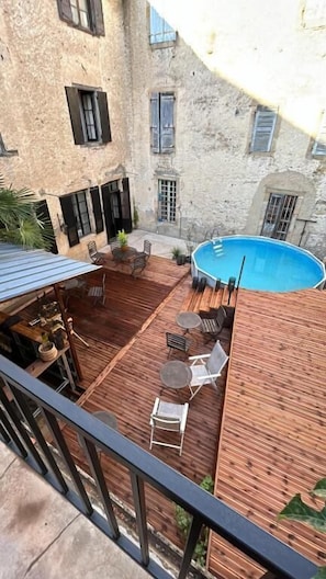 A courtyard with a wooden deck, a pool, and outdoor seating.