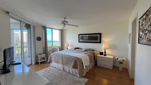 A bedroom with a bed, bedside tables, a ceiling fan, a TV, and a view of the outdoors. - Apartment in Paradise! Feb/March 2027 availability! (Naples)