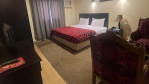 A hotel room with a bed, a desk, a chair, a lamp, and a ceiling light. - Al Orouba Hotel (Riyadh)