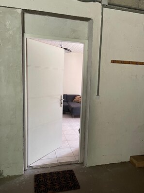 A doorway leading to a room with a sofa and a patterned mat on the floor.