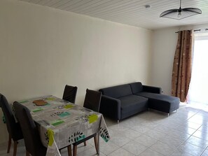A dining area with a table and chairs, a sofa, and a ceiling fan.