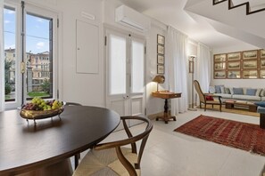 Ein Essbereich mit Tisch, Stühlen, einer Obstschale und Blick auf Gebäude.