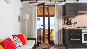 Ein Wohnzimmer mit Sofa, ein Essbereich mit Tisch, eine Küche mit Schränken und Herd sowie ein Balkon mit Aussicht.