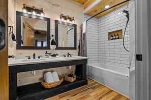 Un baño con dos lavamanos, un espejo grande, una ducha y techo de madera.