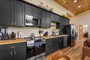 A modern kitchen with dark cabinets, stainless steel appliances, and a wooden countertop. - Nice Views, Theater, Gameroom, Arcade, Hot Tub (Pigeon Forge)