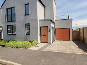 A modern two-story building with a grey facade, a brown door, and an orange garage door. - Eden's Bloomdale (St Austell)