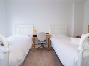 A bedroom with two single beds, a desk, a chair, and a nightstand. - Eden's Bloomdale (St Austell)