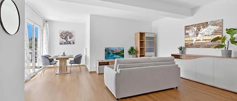 Una sala de estar moderna con sofá, mesa de comedor, sillas y obras de arte.