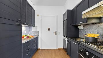 Une cuisine moderne avec des meubles de couleur sombre, une porte blanche et une cuisinière avec des casseroles et des poêles.