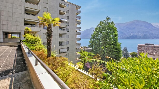 Een modern gebouw met balkons met uitzicht op een waterpartij en bergen.