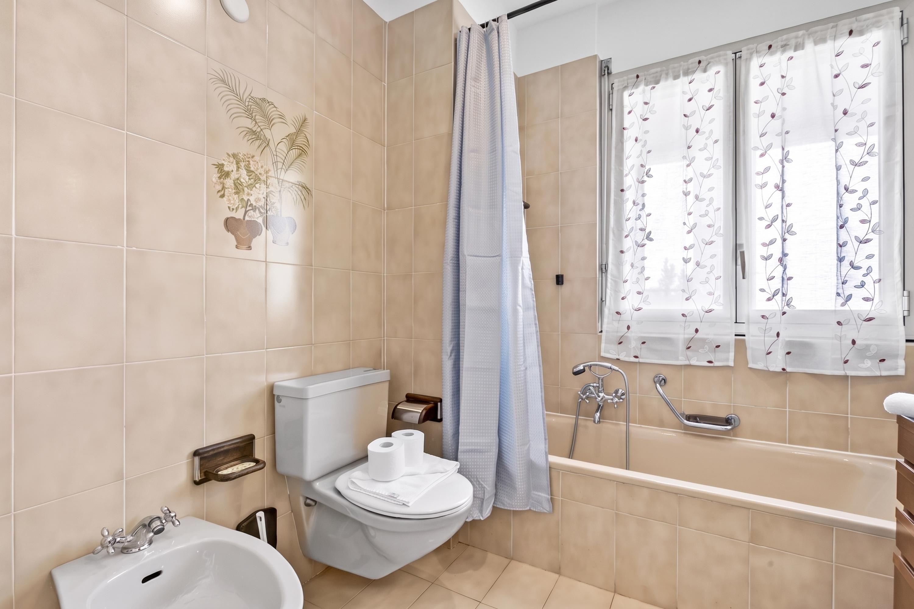 A bathroom with a toilet, bidet, sink, and bathtub.