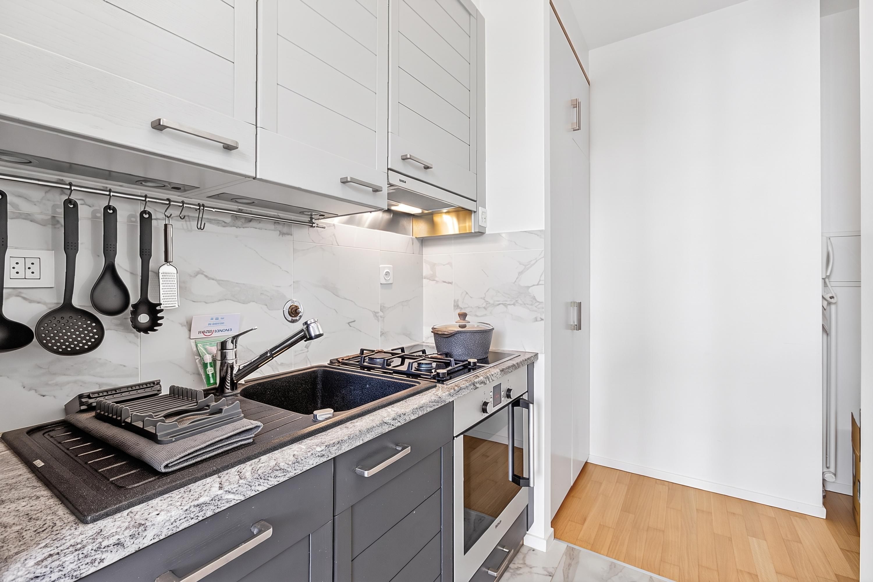 A modern kitchen with a granite countertop, stainless steel appliances, and a marble backsplash.
