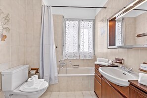 Ein modernes Badezimmer mit Toilette, Bidet, Badewanne und einem großen Spiegel.