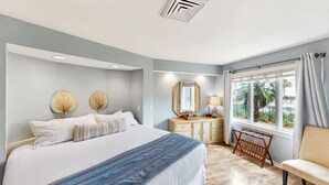 Een slaapkamer met een bed, nachtkastjes, een spiegel, een raam met gordijnen en uitzicht op de omgeving.