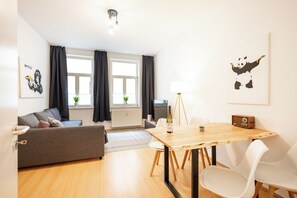 Moderni olohuone, jossa on sohva, puinen ruokapöytä ja televisio.