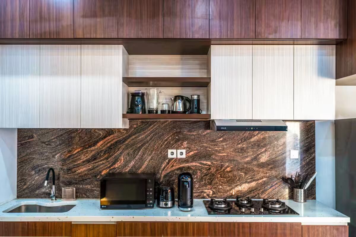 A modern kitchen with a marble backsplash, built-in appliances, and wooden cabinets.