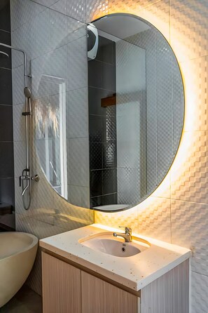 A modern bathroom with a round mirror, a shower, and a sink. - 2BR Villa w private Pool - Queen (Seminyak)