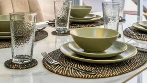 A dining table set with clear glasses, green bowls, and woven placemats. - 2BR Villa w private Pool - Queen (Seminyak)