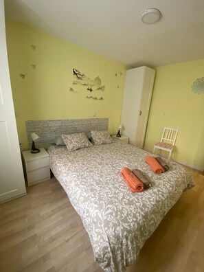 A bedroom with a bed, nightstands, a wardrobe, and a chair.