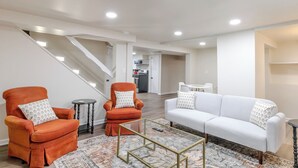 Una sala de estar moderna con un sofá, dos sillones, una mesa de centro y una escalera.