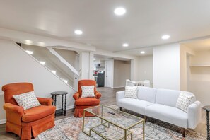 Un salon moderne comprenant un canapé, deux fauteuils, une table basse et un escalier.