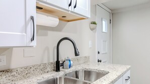 Una cocina con armarios blancos, encimera de granito, pileta de acero inoxidable y grifo negro.