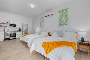 Una habitación de hotel moderna con dos camas, una kitchenette y un baño.