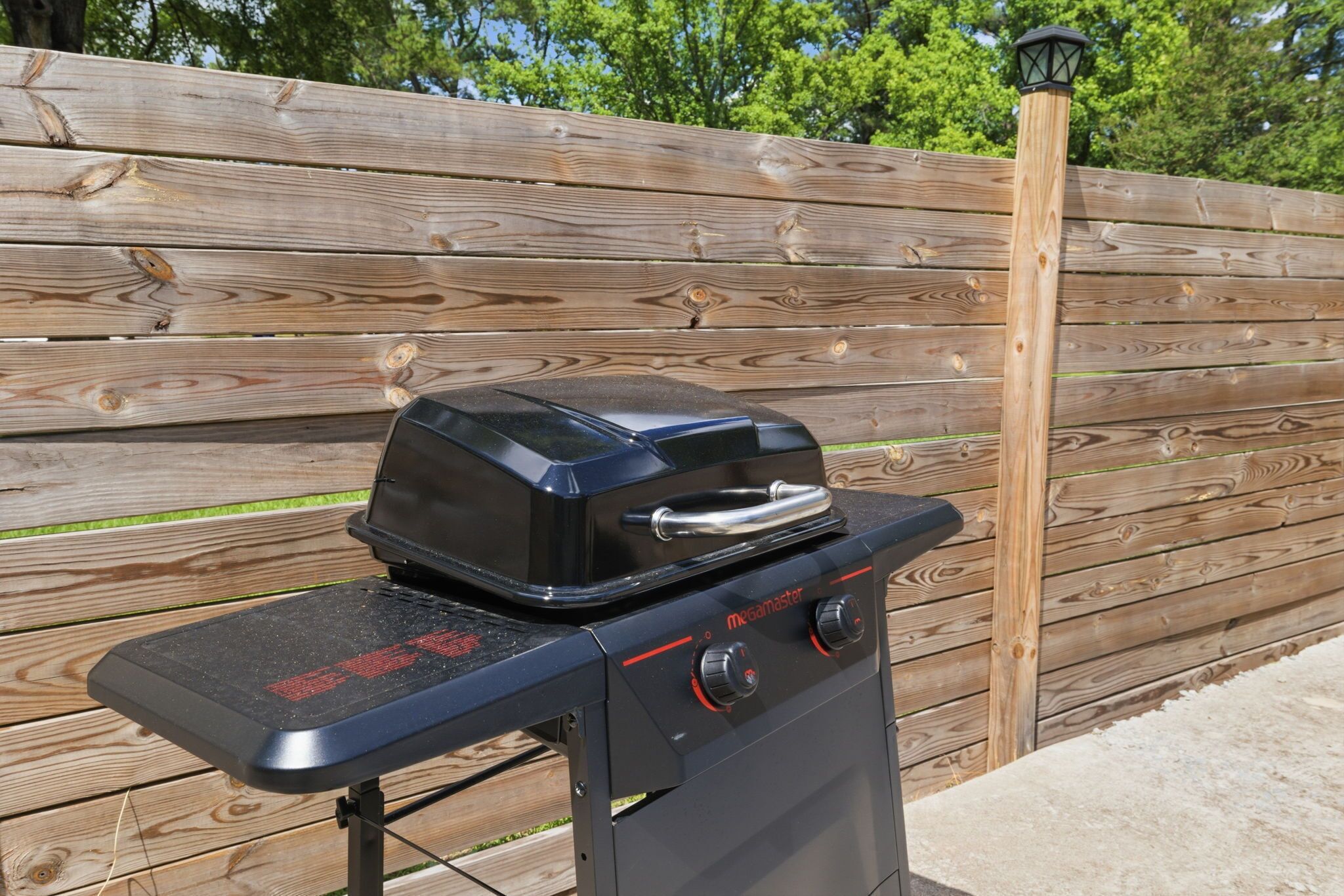 A black outdoor grill with a digital display and control knobs, placed on a metal stand.